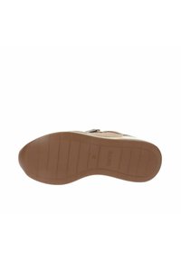 Suola beige della scarpa con una suola in gomma testurizzata, caratterizzata da un motivo antiscivolo e una punta arrotondata. La parte inferiore mostra il nome del marchio, "SKECHERS."
