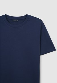 T-shirt a maniche corte di colore blu navy realizzato in cotone, con scollatura rotonda e texture liscia. Etichetta visibile all'interno del colletto.