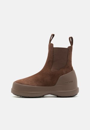 Braune Wildleder-Stiefeletten mit runder Zehenpartie, elastischen Seiteneinsätzen und einer festen Gummisohle. Verfügt über eine Zuglasche für ein einfaches Anziehen.
