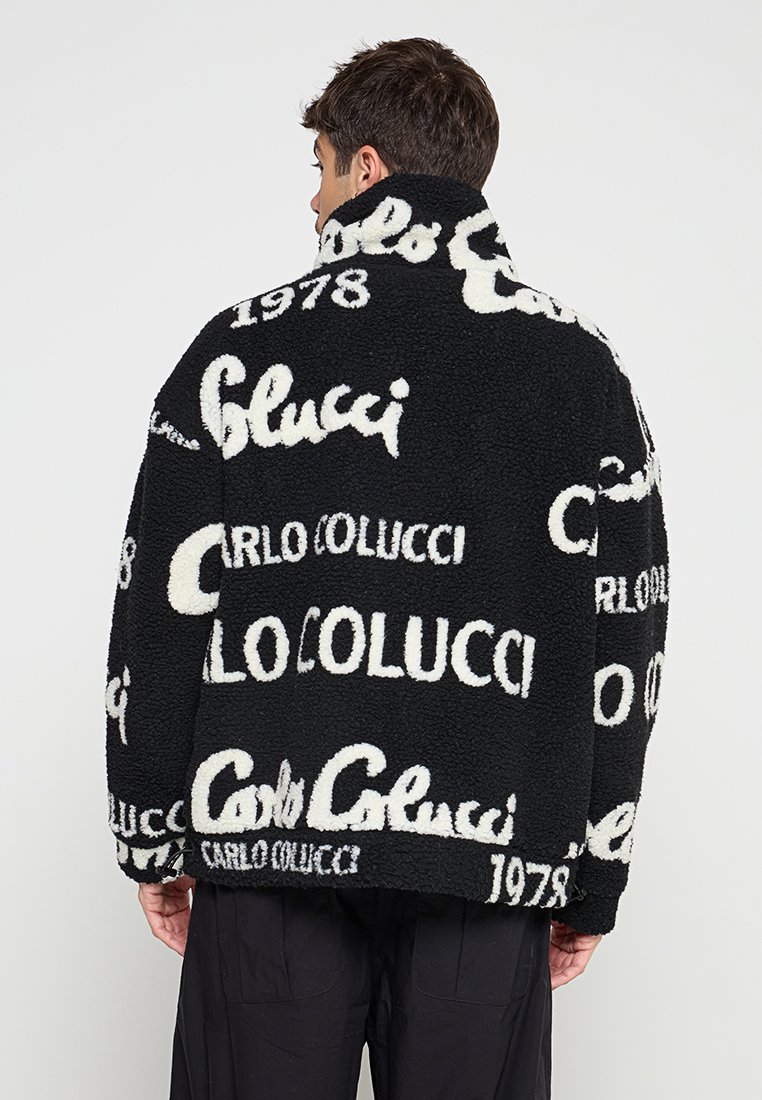 Schwarze Fleecejacke mit weißen Aufdruck, einschließlich "Carlo Colucci" und "1978", mit einer weichen, strukturierten Oberfläche und lockerer Passform.