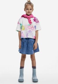 Maglietta bianca a maniche corte con stampe colorate di frutta; gonna di denim; stivali di gomma grigi; sciarpa rosa. Outfit complessivo casual e giocoso per bambini.