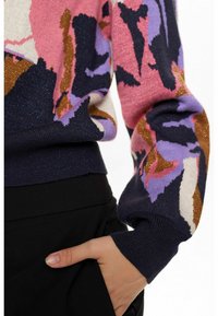 Pinti megztinis su daugiakryptėmis gėlėmis, kuriame vyrauja rožinė, violetinė ir tamsiai mėlyna spalvos; su blizgia apdaila ir raukšlėtomis rankovėmis.