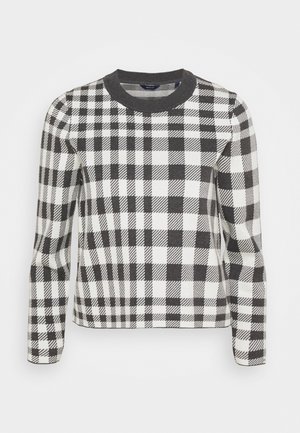 Mustavalkoinen ruudullinen neule, jossa on ribattu pyöreä pääntie, pitkät hihat ja vartaloa myötäilevä muoto. Kuvio koostuu vuorotellen esiintyvistä neliöistä ja raidoista.