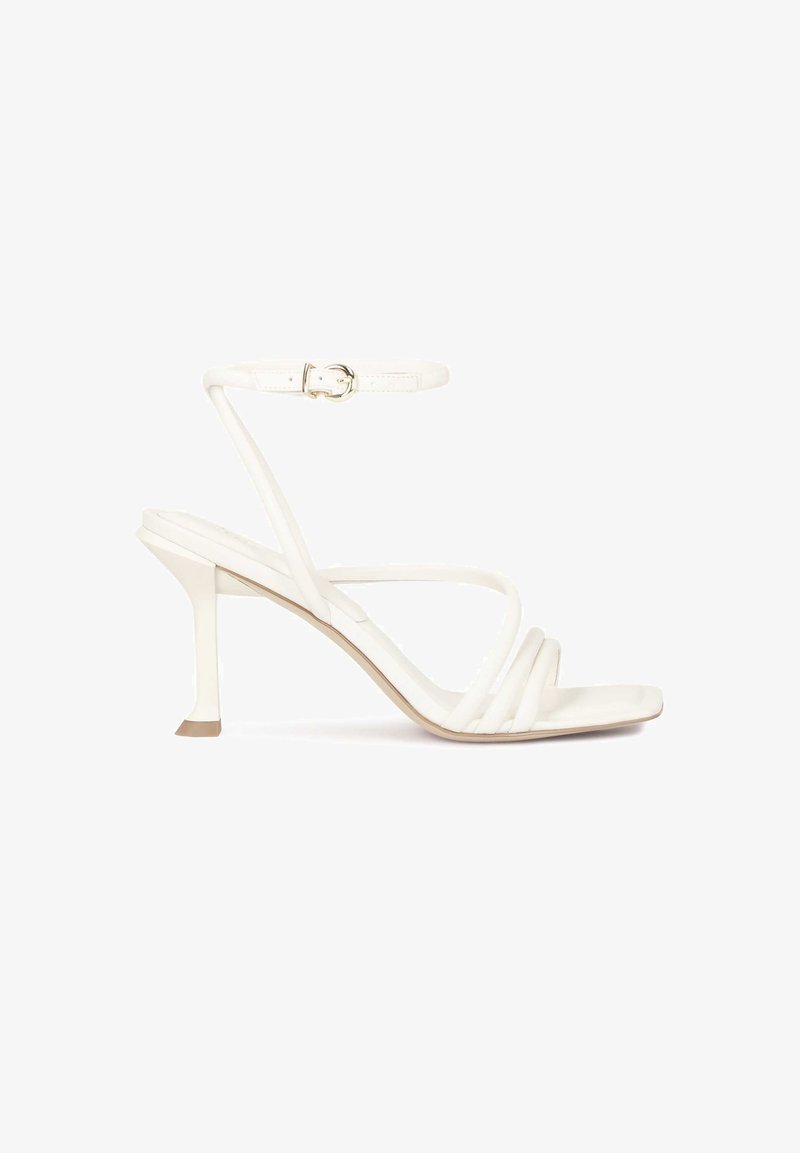 Bela sandala s peto, z usnjeno naramnico in kvadratnim prstom, tanka naramnica z zaponko ter oblikovano peta. Gladka tekstura po celotni površini.
