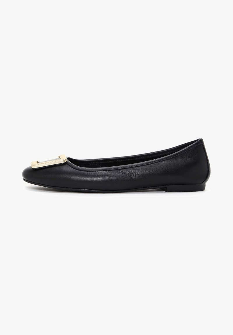 Ballerine en cuir noir avec un bout arrondi, ornée d'une décoration dorée à l'avant et d'une semelle basse et flexible.