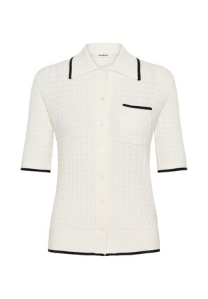 Witte gebreide cardigan met korte mouwen, voorzien van zwarte bies langs de kraag, zak, manchetten en zoom. De cardigan heeft knopen aan de voorkant en een borstzak.