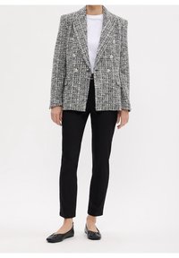 Šedá a bílá tweedová dvouřadá blazer s velkými stříbrnými knoflíky, spárovaná s černými úzkými kalhotami a černými balerínami. Minimalistický design.