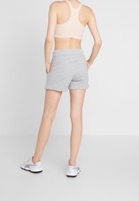 Grå bomullsshorts med avslappnad passform, med elastisk midja och sidofickor, i kombination med vita sportskor.