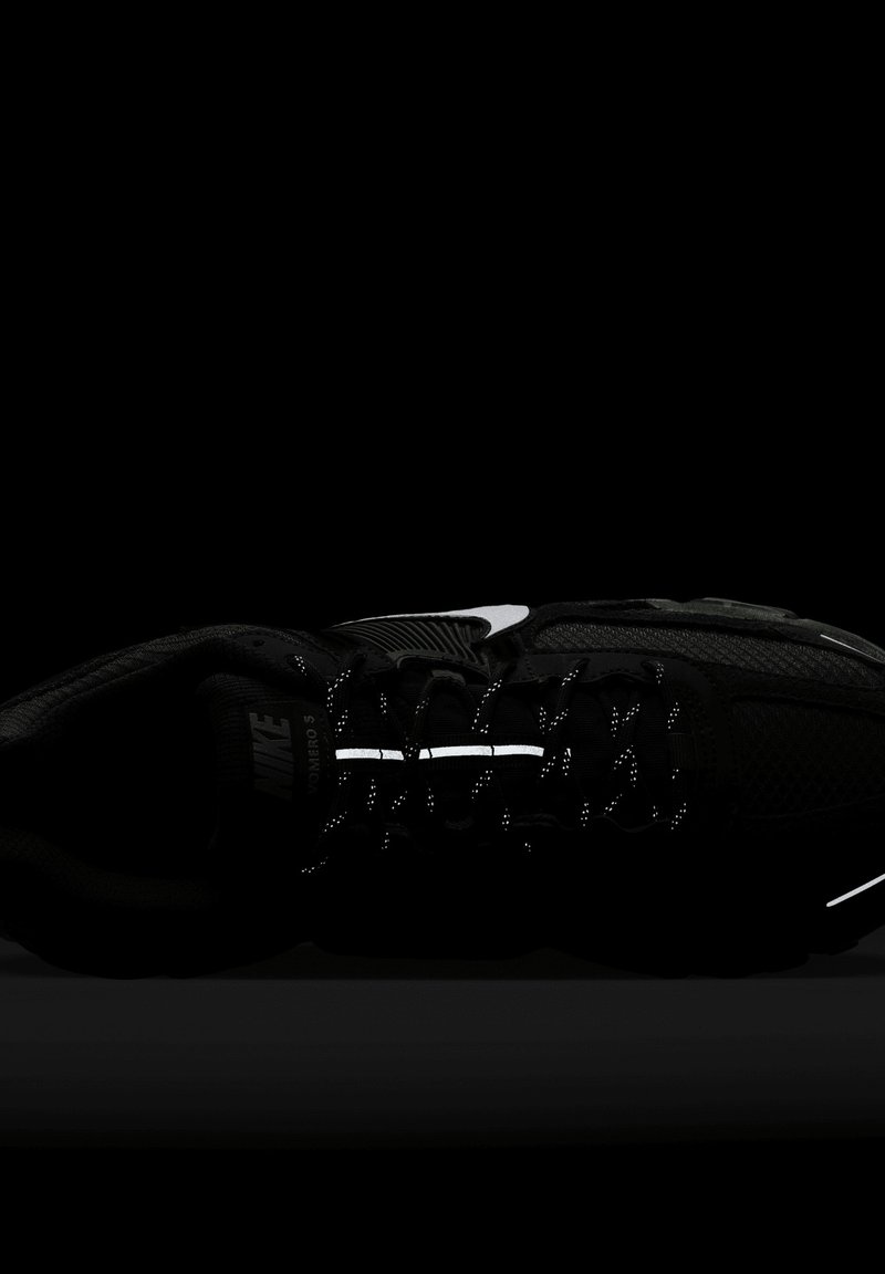 Chaussures de course Nike Zoom Vomero 5 en noir avec accents réfléchissants, tige en mesh, semelle rembourrée et détail de logo blanc contrastant.