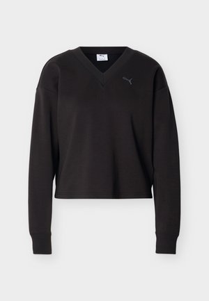 Bluză neagră crop cu mâneci lungi, decolteu în V și mic logo Puma pe pieptul stâng, afișată pe un fundal alb simplu.