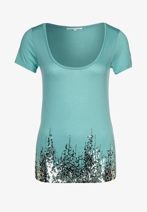 Camiseta de manga corta turquesa con escote redondeado y detalles de degradado de lentejuelas plateadas en la parte inferior, creando una apariencia texturizada.