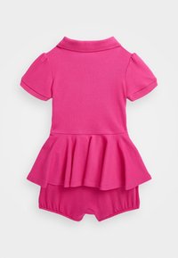 Růžový bavlněný overal s krátkými rukávy, polokošilovým límcem a rozšířeným peplum pasem. Má přiléhavý spodní díl a hladkou texturu.