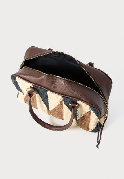 Sac en cuir marron et en tissu tissé avec des triangles géométriques beige, crème et bleu foncé, fermeture éclair ouverte et double poignées sur fond blanc.