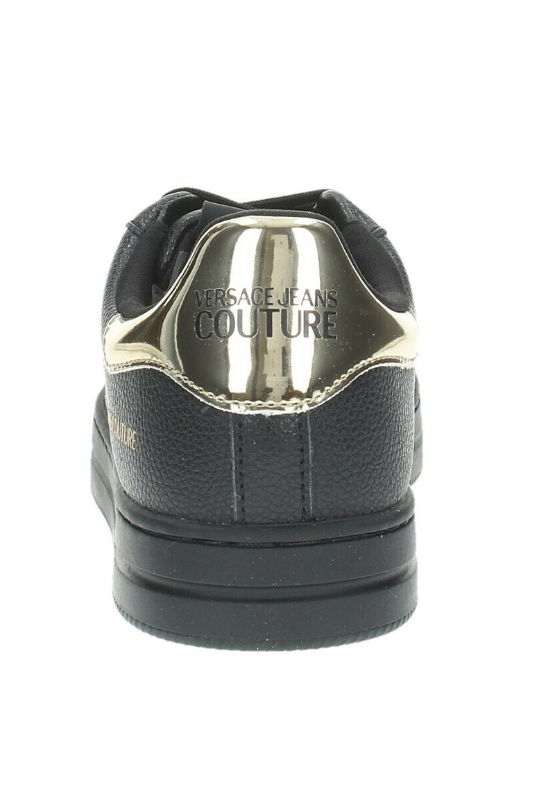 Baskets noires avec un dessus en cuir texturé, accent doré brillant au talon, logo "Versace Jeans Couture" embossé, et semelle en caoutchouc plate.