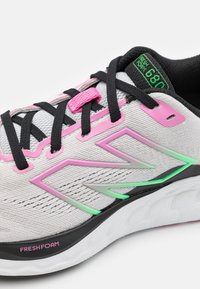 Light grey athletic shoe featuring a breathable upper, pink and green accents, black laces, and a padded collar with "Fresh Foam" branding.