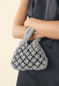 Pilka rankinė su karoliukais, struktūruota trikampio formos, su austu dizainu ir dviem tekstūruotais rankenomis.