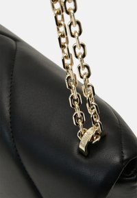 Borsa a tracolla nera in pelle con una catena dorata. Presenta una texture trapuntata e un dettaglio con logo sul fermo.