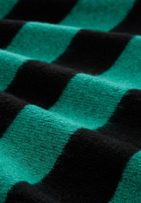 Tkanina w paski z naprzemiennie występującymi pasami w kolorze turkusowym i czarnym. Tekstura wydaje się miękka i puszysta, przypominając materiał wełniany.