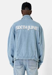 Veste en denim bleu clair à coupe carrée, avec les inscriptions brodées en blanc "SIXTH JUNE" et "PARIS" au dos, dotée de boutons et de poches latérales.