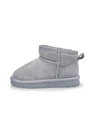 Bottine en suède gris clair avec semelle épaisse, coutures visibles et languette à l'arrière, visible de profil sur fond blanc.