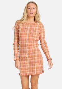 Robe à manches longues dans des nuances de pêche et de rose, présentant un design plissé avec un tissu texturé et des accents de ourlet volanté.