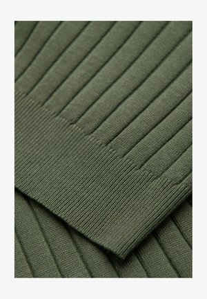Close-up of dark green ribbed knit fabric showing detailed texture and stitching of a folded garment sleeve.