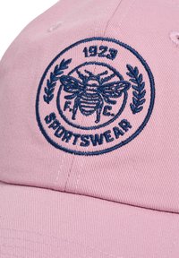 Rosa baseballkeps i bomull, med en marinblå broderad cirkulär logo med en bi och texten "1923 F.C. SPORTSWEAR."