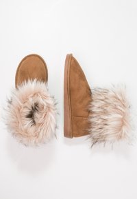 Zapatillas de ante marrón con un suave puño de piel sintética en tonos rosa y blanco, punta redonda y suela texturizada. Las zapatillas están una al lado de la otra.