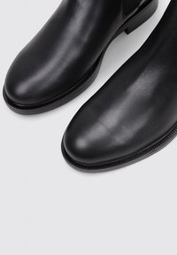 Black leather ankle boots with a smooth finish, rounded toe, elastic side panels, and a textured trim along the sole.