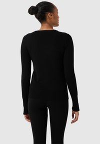 Černý svetr s dlouhým rukávem ve fitted designu, s kulatým výstřihem a žebrovanými manžetami, vyrobený z hladkého pleteného materiálu.
