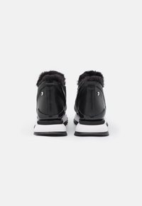 Sorte atletiske sko med en faux fur krave, lavet af læder og syntetisk materiale, hvid sål og et slankt design med sølvfarvet hardware.