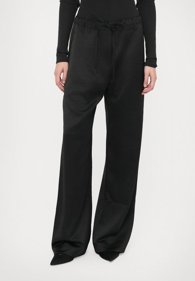 Zwarte wijde broek van zachte stof, met een elastische tailleband en een koord voor verstelbaarheid, en een gladde textuur voor comfort.