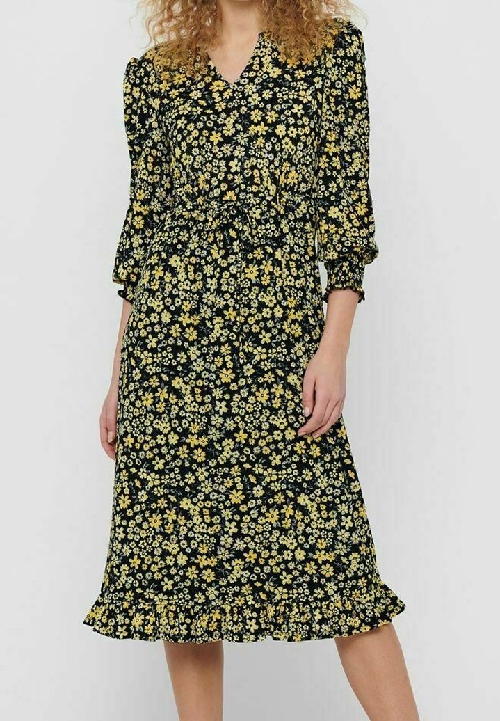 Vestido negro con estampado floral amarillo, escote en forma de V y mangas abullonadas. Presenta una cintura ceñida y un dobladillo con volantes. Textura de tejido suave.
