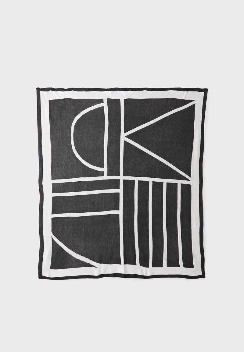 Sort-hvid mønstret tekstil med geometriske former og linjer, en struktureret overflade og kontrasterende kanter.