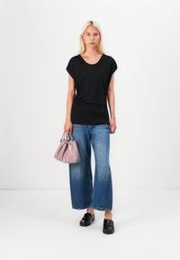Black short-sleeve top, loose fit; light blue wide-leg jeans; small lavender handbag; black slip-on shoes. Simple design, casual look.