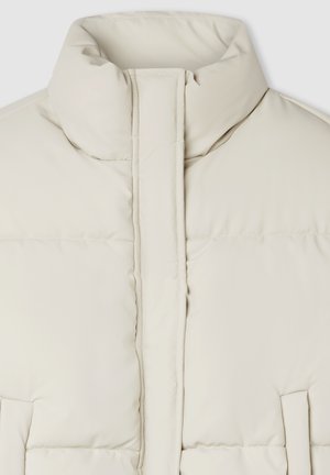 Kremowa pikowana kurtka z wysokim kołnierzem, pionową szwem z przodu i bocznymi kieszeniami, ukazana w zbliżeniu.