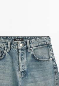 Světle modré džíny z denimu s klasickým pětipocket designem, kovovými detaily a štítkem s názvem "Massimo Dutti" na pasu.