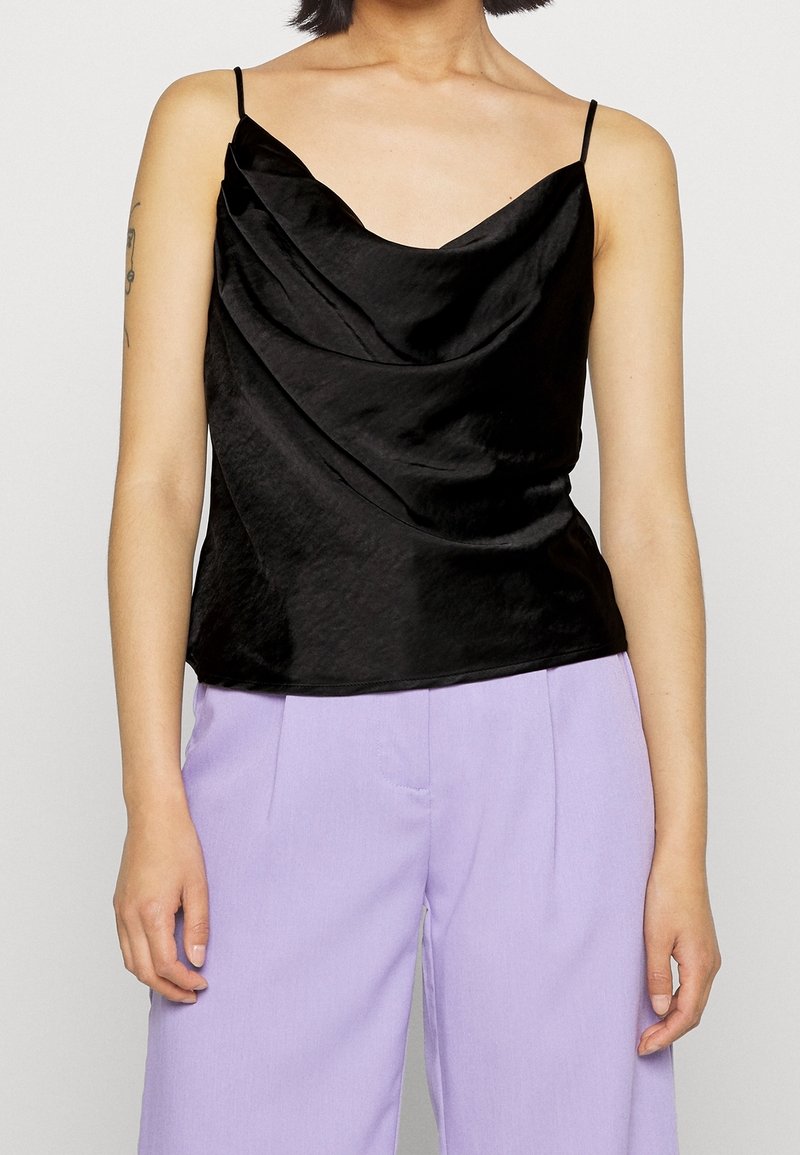 Černá saténová košilka s drapovaným výstřihem a tenkými ramínky, doplněná světle fialovými kalhotami na míru.