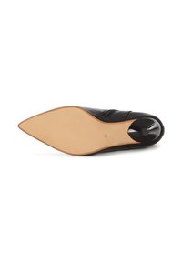 Scarpa in pelle nera con punta affusolata e tacco basso. La suola è beige chiaro con una texture liscia e un piccolo bottone nero decorativo vicino al tacco.