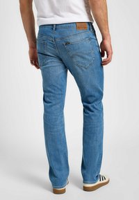 Ljusblå denimjeans med rak benklippning, med en brun läderlapp, två bakfickor och en lätt urtvättad struktur.