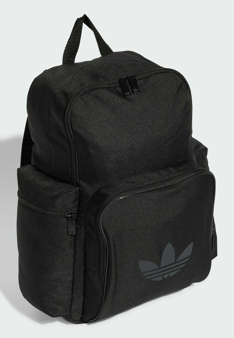 Sac à dos noir en tissu texturé, doté de compartiments zippés et d'un logo légèrement embouti. Poignée supérieure robuste et bretelles rembourrées.