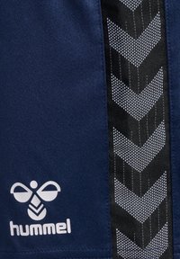 Marineblaue Sportshorts mit weißem Logo, seitlich ein schwarzes Paneel mit einem geometrischen Chevron-Muster in Weiß. Robuster, leichter Stoff.