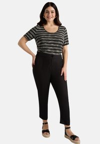Pantalones ligeros negros de cintura alta, combinados con una camiseta de rayas de manga corta en negro, blanco y gris. Los acentos incluyen sandalias planas.