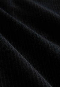 Black corduroy fabric with distinct ribbed texture, featuring soft fibers and smooth drape in varying light.