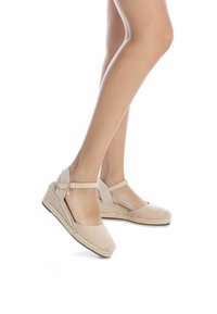Sandalias de cuña en espadrille de color beige con una correa en el tobillo texturizada, media suela de cuerda trenzada y punta redondeada. Material suave similar a gamuza.