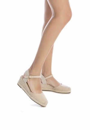 Sandalias de cuña en espadrille de color beige con una correa en el tobillo texturizada, media suela de cuerda trenzada y punta redondeada. Material suave similar a gamuza.