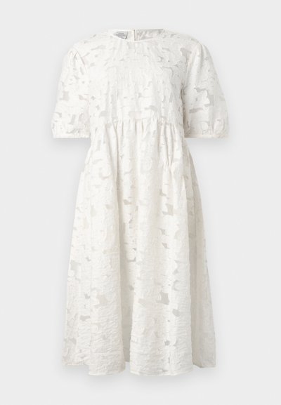 Vestido blanco con una tela texturizada de patrón floral, mangas cortas abullonadas y cuello redondo. La silueta es de corte holgado.