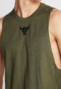 Camiseta sin mangas de color verde oliva hecha de tela texturizada. Presenta un escote redondo y un logo de toro negro en el pecho.
