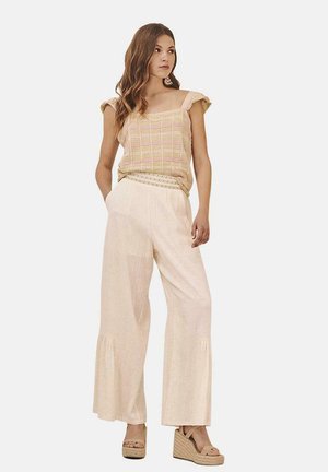 Top corto de color beige claro con textura tejida y rayas rosas, combinado con pantalones de pierna ancha color crema de cintura alta con dobladillos acampanados y cuñas de esparto.