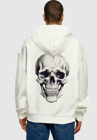 White hoodie featuring a large, graphic black and gray skull design on the back. Soft material with a loose fit and kangaroo pocket.